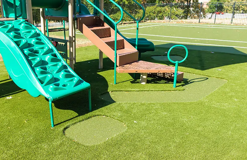 Green slide installed on artificial grass